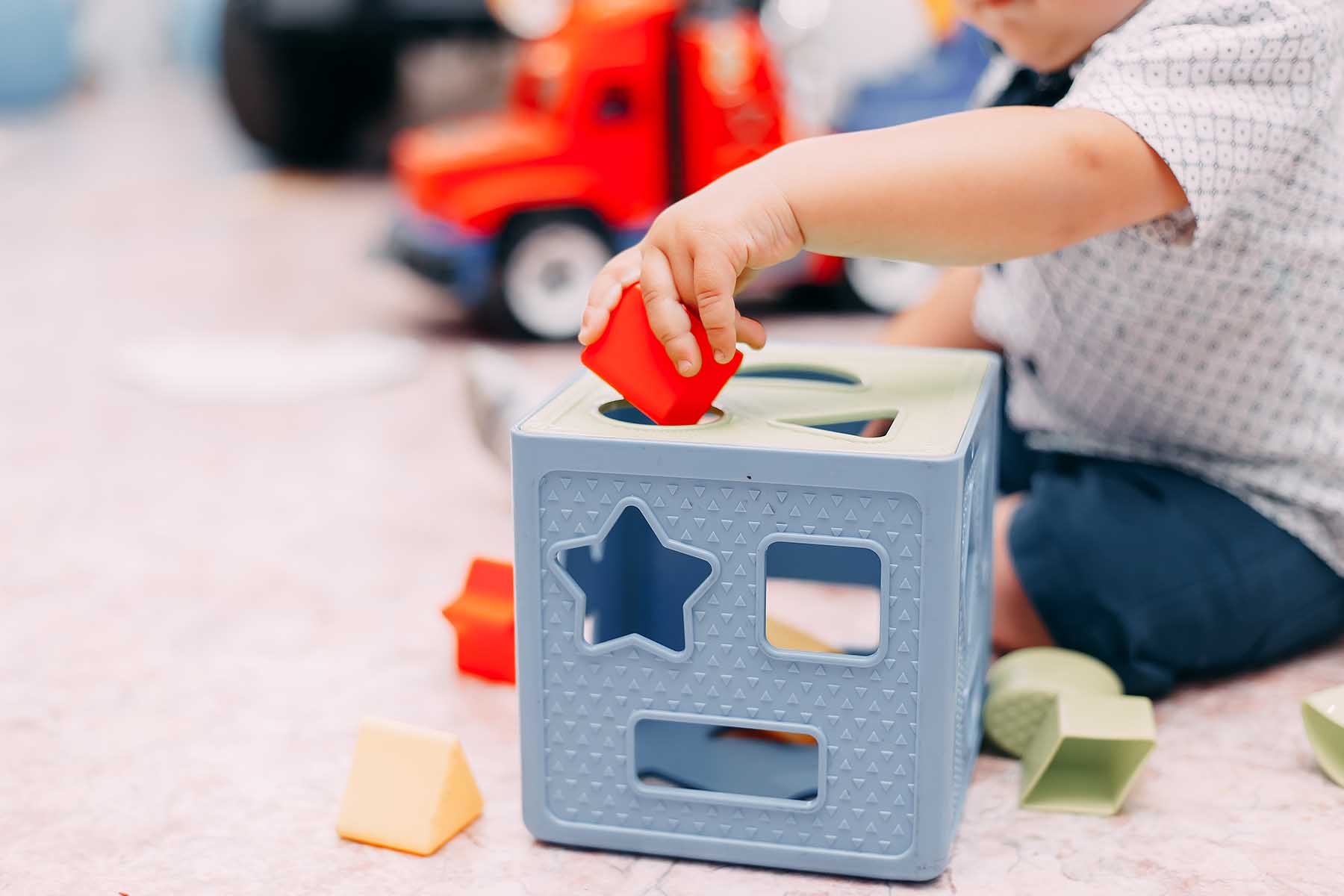 A young toddler plays with blocks and a box on the floor