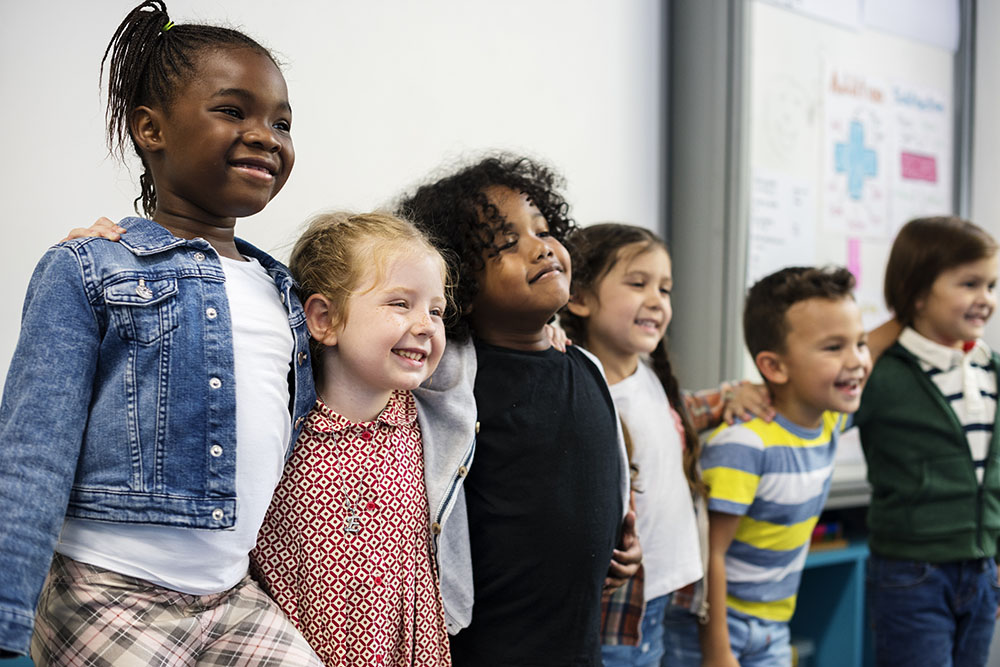 Group of diverse kindergarten students standing together in classroom