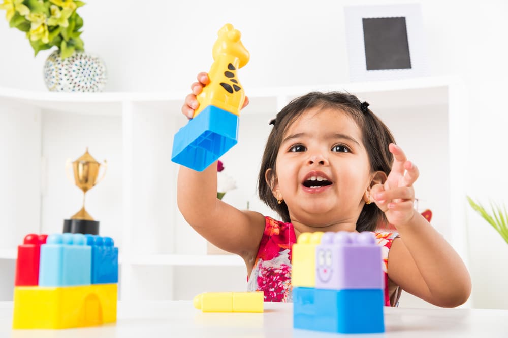 A young girl plays with multi colored blocks